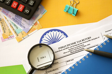 Indian income tax return blank form with pen and indian rupees bills on indian country flag close...