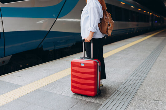 Woman with suitcase waiting to enter into the train on station. Outdoor adventure travel by train concept. Travel to vacation by train