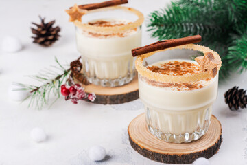 Homemade eggnog with cinnamon in glass on wooden table. Typical Christmas drink