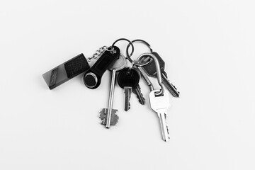 a bunch of door keys with a magnetic security key and epoxy wooden keychain on a white background top view, black and white photo