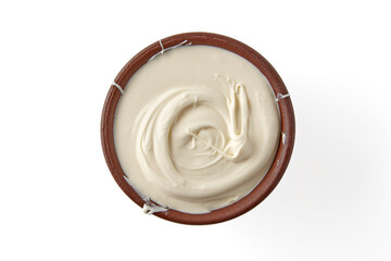 Sour cream in a brown clay bowl isolated on a white background. Top view with copy space