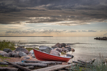 small boat on a beach, Image shows a small red dingy on a beach next to a wooden boat ramp with a...