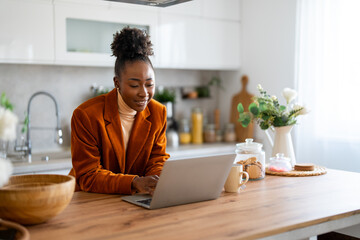 Confident businesswoman doing research over wireless computer on desk while sitting in home office.