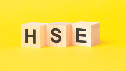 HSE - Health and Safety Executive symbol. wooden cubes with words. beautiful yellow background. business concept. copy space.