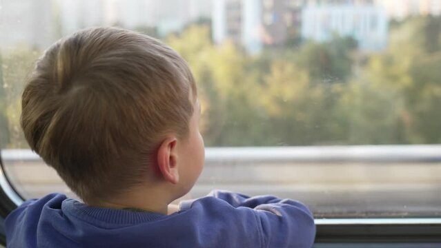 A five-year-old boy rides and looks out the window