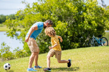 Active father son playing football in summer. Father and child son teaming up outdoor. Father dad...