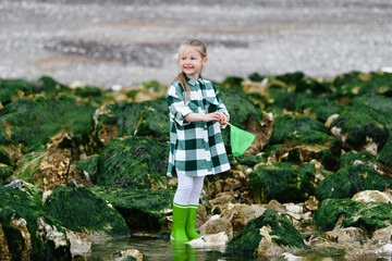 Girl in rubber boots catches crabs with fishing nets - obrazy, fototapety, plakaty