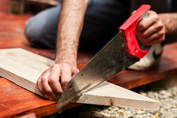 Carpenter cutting wooden board closeup