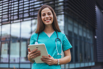 Portrait of happy young female nurse with folded arms standing in hospital. Confident doctor woman...