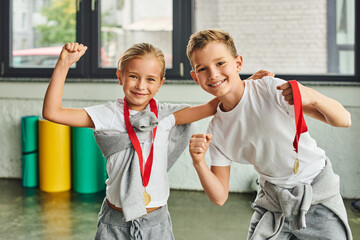 happy preadolescent boy and girl having great time wearing golden medals and smiling at camera