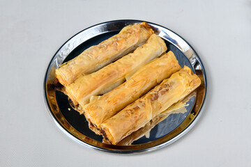 Turkish style meat stuffed filo dough borek served kol boregi. Cheese and minced pie are sliced on a marble background. Turkish name: Kol Boregi, ispanakli, kiymali, Su Boregi