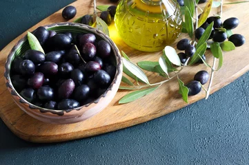 Foto op Plexiglas Olive nere in una ciotola, nell'olio e nel ramo delle olive. Concetto di cibo sano. Vista dall'alto. Copia spazio. © bursucgrazziela
