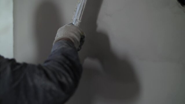 Worker leveling the wall with a trowel