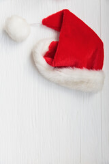 Obraz na płótnie Canvas Santa Claus hat on white wooden background. New Year and Christmas.