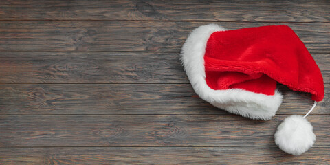 Obraz na płótnie Canvas Santa Claus hat on dark wooden background. Top view, long banner with copy space