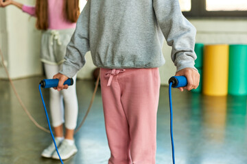 cropped view of preadolescent girls in sportswear posing with skipping ropes, child sport