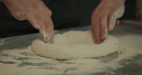 Skilled fingers with gentle yet purposeful motions working with dough.