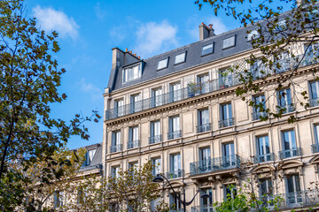 Façade d'un immeuble résidentiel de style classique à Paris situé dans une avenue bordée d'arbres. Concept de marché immobilier d'habitation pour les logements anciens en France - obrazy, fototapety, plakaty