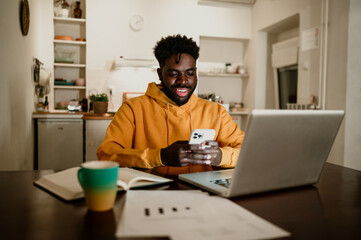 Fototapeta na wymiar A cheerful african american social media marketer is working at night from home remotely.