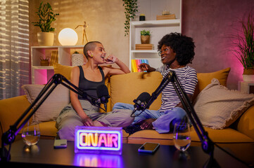 Two diverse women recording episode of internet podcast in a modern studio