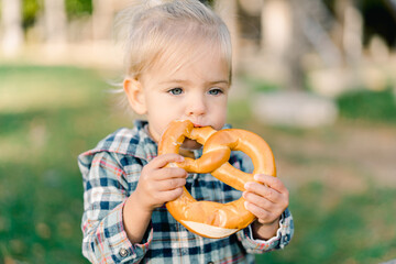 Little girl eating a big pretzel holding it with both hands