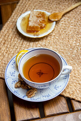 Morning setup on wooden table at balcony, books to read, cup of natural tea, teapot, organic honey from farm, fresh green tea leaves and organic fruits, in background nice view on small city park 