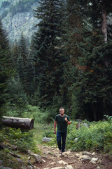 Male hiker with retro backpack. A tourist walks along a mountain path in the middle of the forest. Front view. A gloomy summer day. Georgia. the way to the Shdugra waterfall
