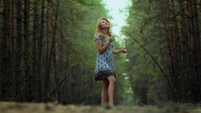 Romantic girl in a summer sundress walking in the forest enjoying life positive model outdoors enjoys her life