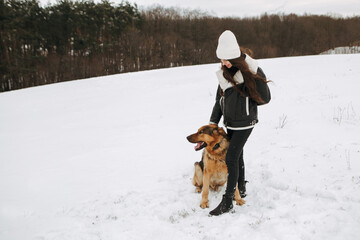 Young woman walk the dog German Shepherd in winter field forest, running playing with snow, training the animal in harsh conditions, wind blowing. Christmas Time, New Year