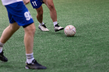 Mini soccer football players playing game in indoor stadium on artificial turf.