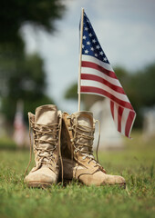 Old military combat boots against American flag in the background. Memorial Day or Veterans Day, sacrifice concept. - 674094610
