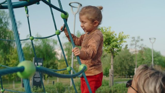 Young happy mother and baby on a carousel in a playground. High quality 4k footage