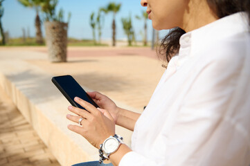 Close up of business woman using smartphone and tapping screen while chatting online, copy space for mobile application