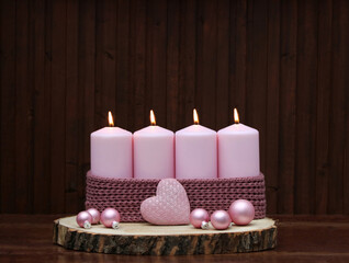 Vierter Advent: Adventsdekoration auf eine
 Holzscheibe dekoriert mit rosa Kerzen und...
