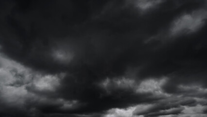 Obraz premium dark dramatic sky with black stormy clouds before rain or snow as abstract background, extreme weather, the sun shines through the clouds, high contrast photo