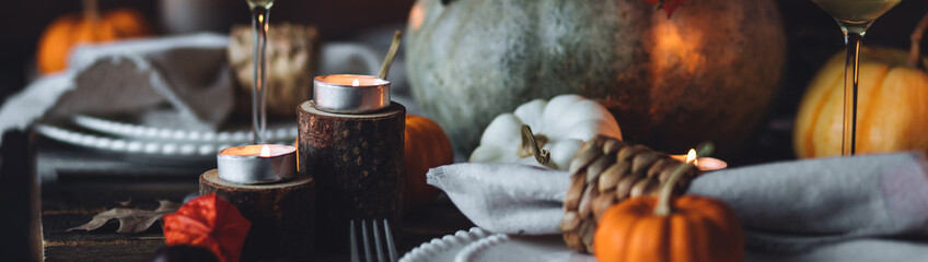 Atmospheric autumn elegant beautiful table setting with pumpkins for a wedding or thanksgiving family celebration. Fall decoration countryside rustic style, cozy home atmosphere , candles, wine banner