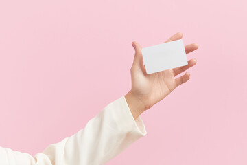 Womans hand touch a white blank business card that floats on a pink background. Flat lay of a...