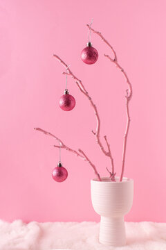 Painted wooden branch with glittering pink ornament balls in white vase on a fluffy fur and pastel pink background. Christmas decoration concept. Holiday home decoration concept. Pink Christmas.