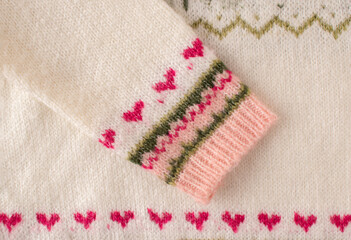 Warm woolen Christmas sweater sleeve with red hearts. Close up. Flat lay. Funny Christmas concept.