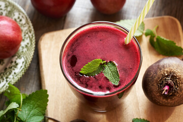 A glass of red beet juice with fresh apples