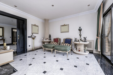 Small living room in a luxury home with access to several rooms, polished marble floors, upholstered armchairs, decorative statues and hardwood furniture
