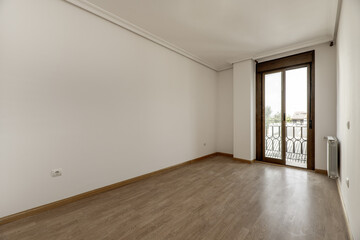 Empty living room or bedroom with white painted walls, double sliding door window with balcony, plaster molding on the ceiling and light wooden and parquet floors