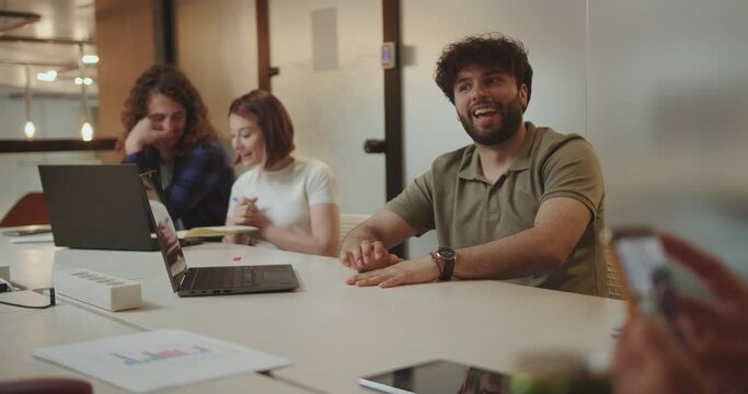 Handsome employee having fun conversation with his teammates during late night meeting at the office.