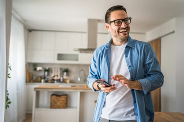 adult man with eyeglasses stand at home use mobile phone sms texting
