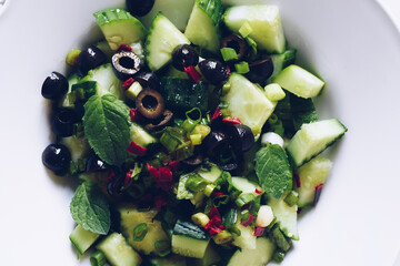 Healthy salad with fresh vegetables - cucumber, black olives, mint and red hot chilli pepper on a...