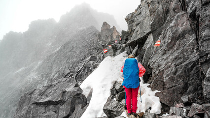 Ein Wanderin bei der Alpenüberquerung im Schnee und schlechter Witterung am Pitztaler Jöchl.