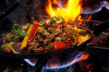 mexican food smoking chicken and beef fajitas on sizzling plate with fire and smoke