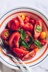 Healthy salad with different types of tomatoes and basil 