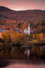Fototapeta na wymiar Autumn colors surround a church in Island Pond, Vermont