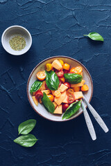 Healthy salad with tomatoes cherry, melon and basil in a grey bowl